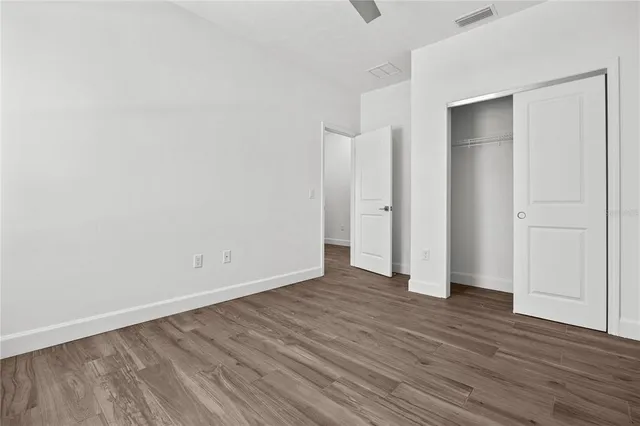 a view of an empty room with wooden floor and closet