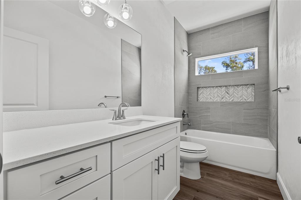 1132 Southwest 67th Drive Gainesville, FL 32607 - Photo 25 of 30 a bathroom with a granite countertop sink a toilet and a bathtub