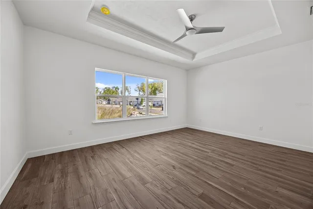 an empty room with windows and ceiling fan
