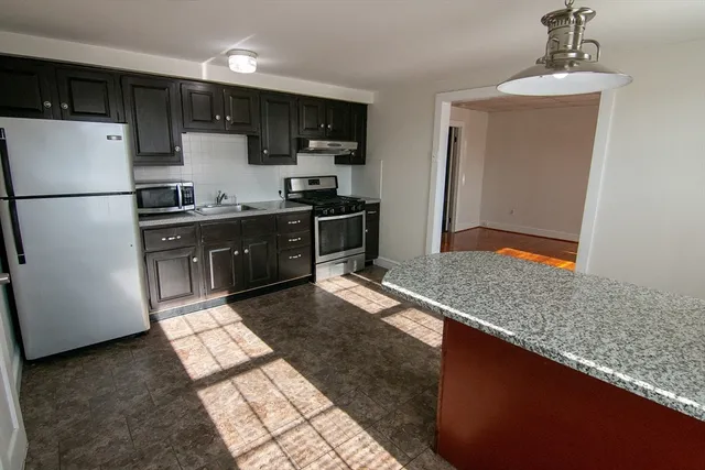 a kitchen with granite countertop a refrigerator and a sink