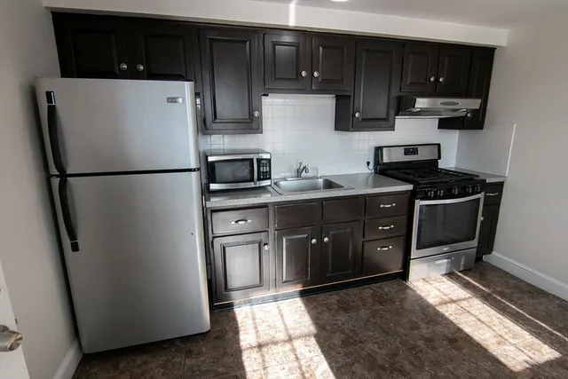 a kitchen with stainless steel appliances granite countertop a refrigerator a stove a sink and a cabinets