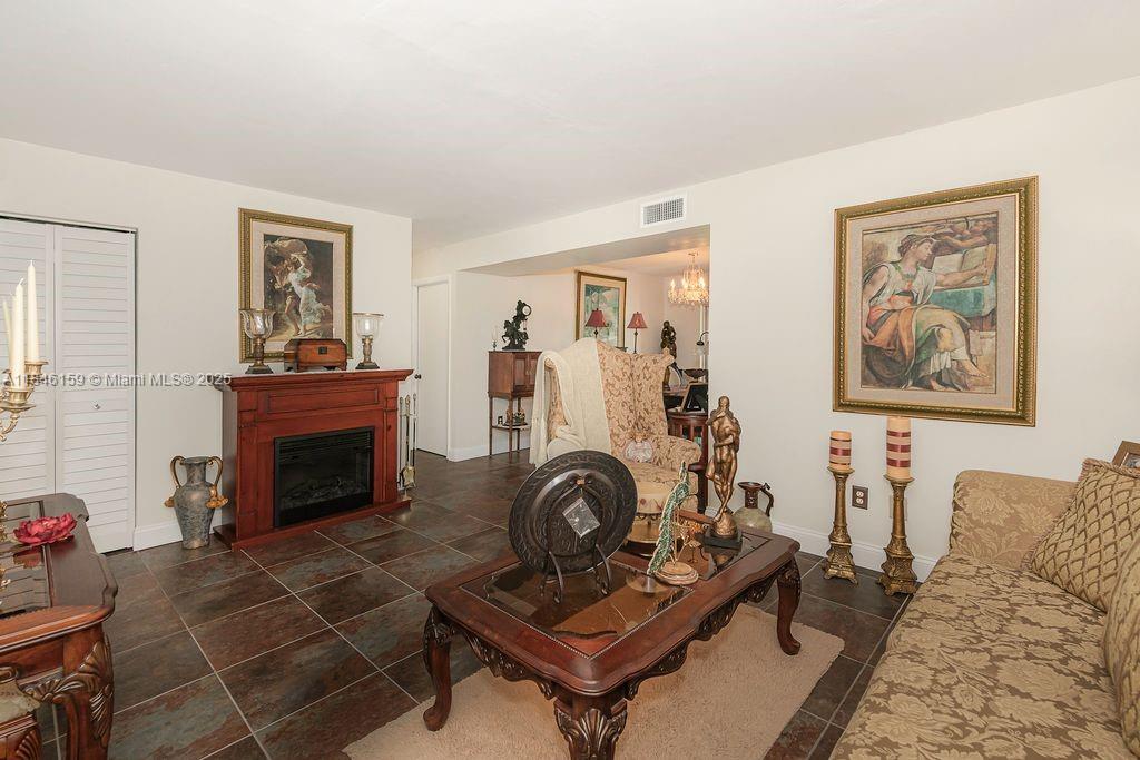 8401 Southwest 107th Avenue, Unit 214E Miami, FL 33173 - Photo 11 of 28 a living room with furniture a fireplace and paintings on the wall
