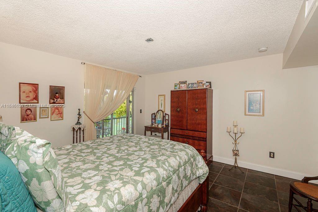 8401 Southwest 107th Avenue, Unit 214E Miami, FL 33173 - Photo 18 of 28 a bed sitting in a bedroom and chandelier