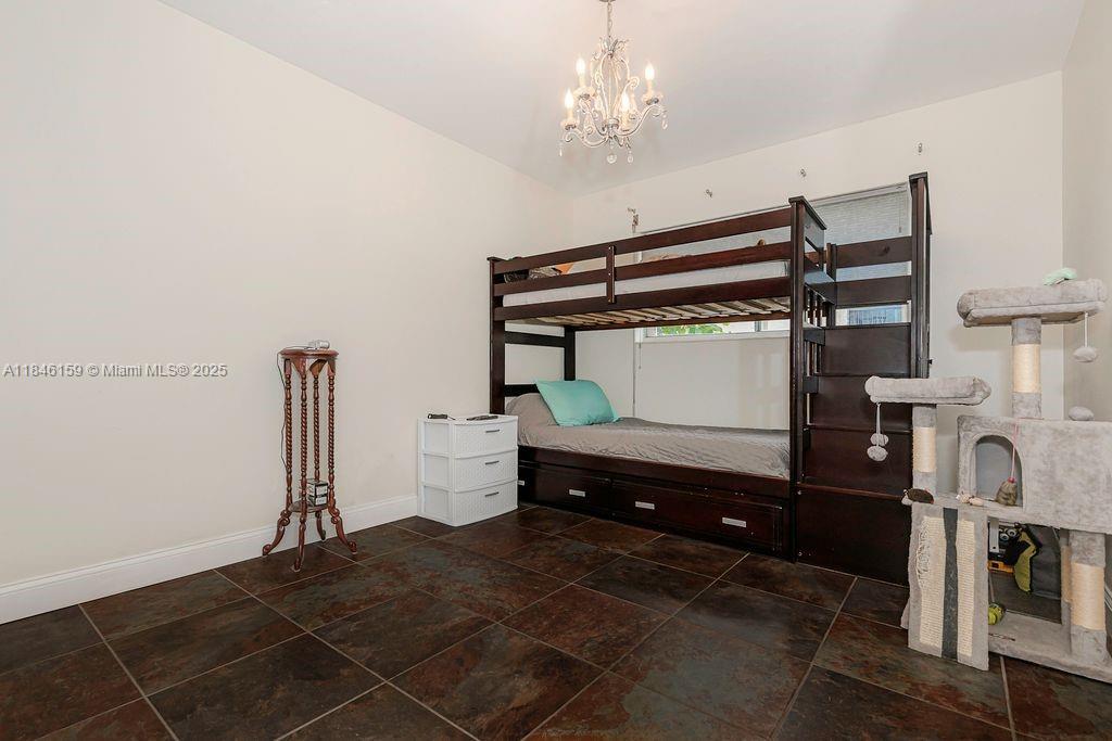 8401 Southwest 107th Avenue, Unit 214E Miami, FL 33173 - Photo 21 of 28 a bedroom with a bed and a chandelier