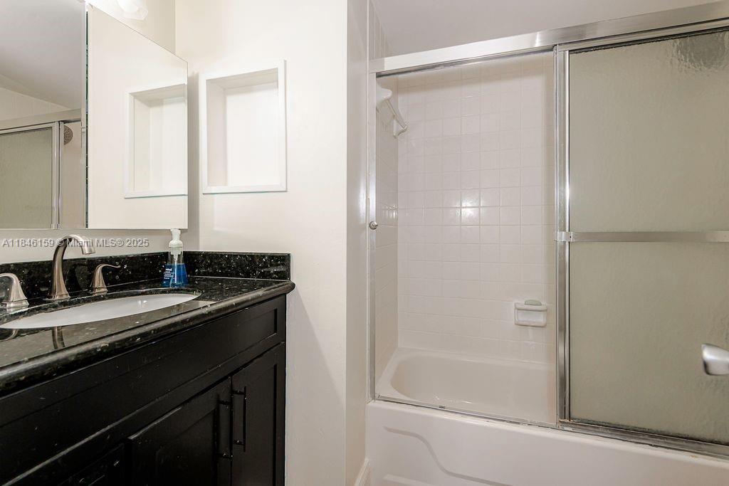 8401 Southwest 107th Avenue, Unit 214E Miami, FL 33173 - Photo 24 of 28 a bathroom with a granite countertop sink mirror and a bathtub