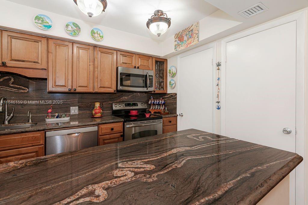 8401 Southwest 107th Avenue, Unit 214E Miami, FL 33173 - Photo 28 of 28 a kitchen with stainless steel appliances granite countertop a stove a sink and a microwave