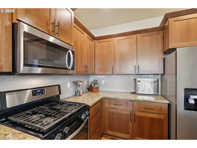 a kitchen with stainless steel appliances granite countertop a stove a microwave and a refrigerator
