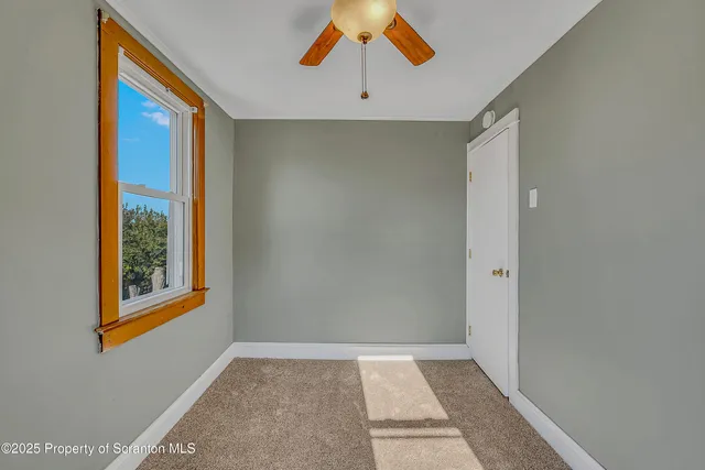 a view of an empty room with window and closet