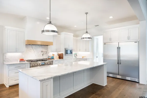 a kitchen with stainless steel appliances kitchen island granite countertop a sink a center island a stove a refrigerator and a center island