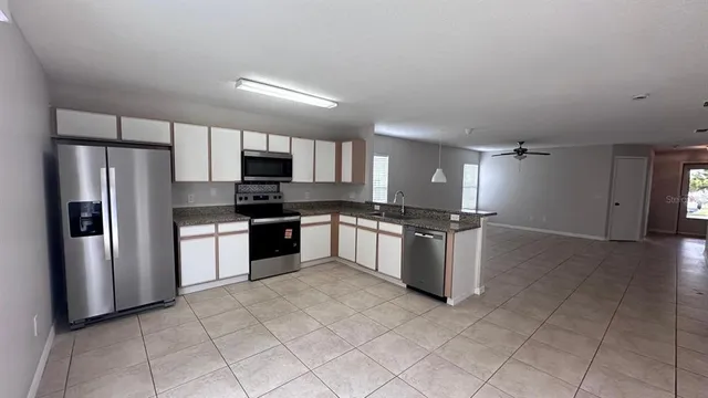 a kitchen with granite countertop a refrigerator and a stove top oven