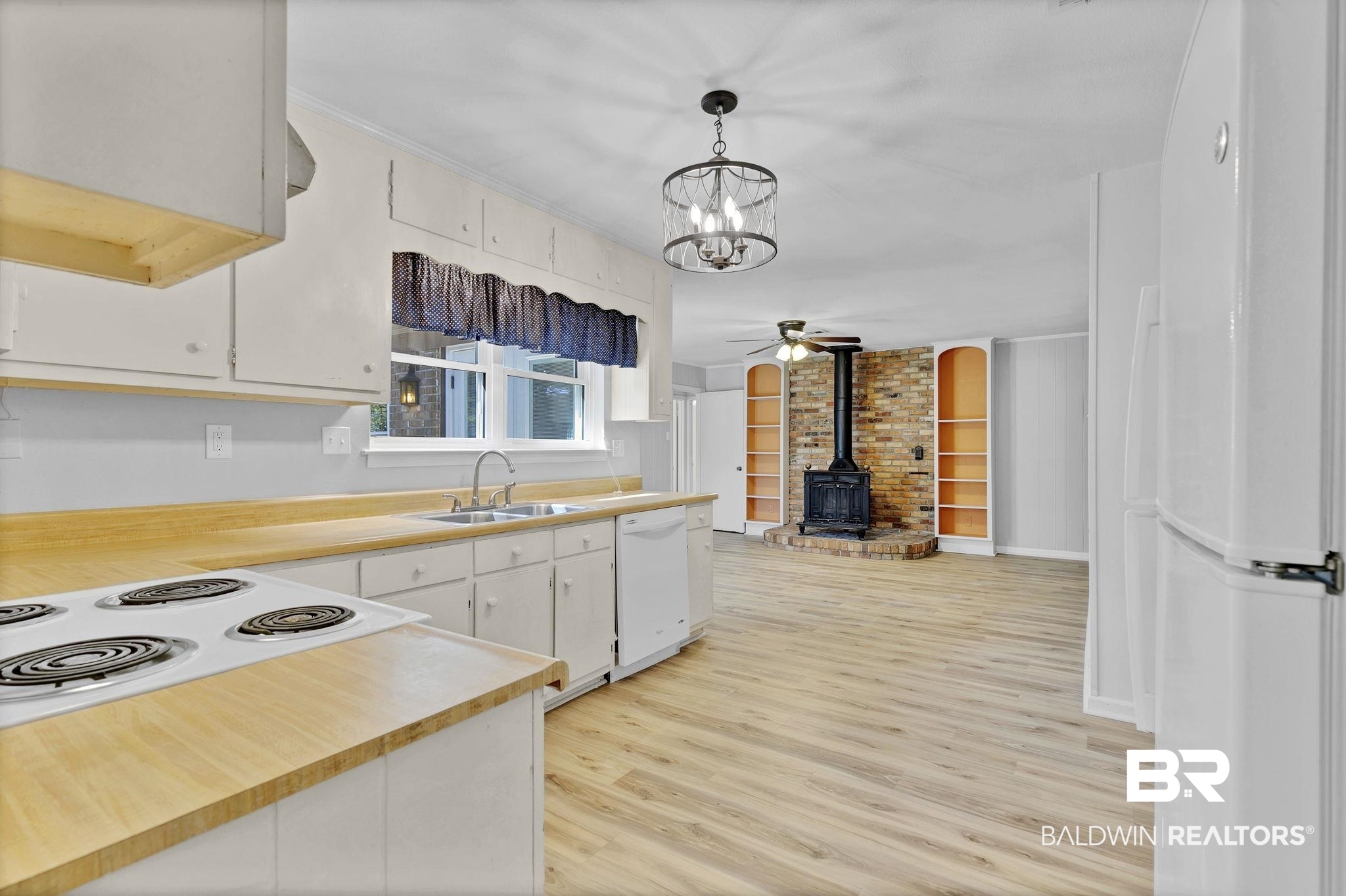 5817 Woodgate Road Mobile, AL 36609 - Photo 21 of 85 Kitchen with white appliances, a wood stove, light countertops, light wood-style floors, and a sink