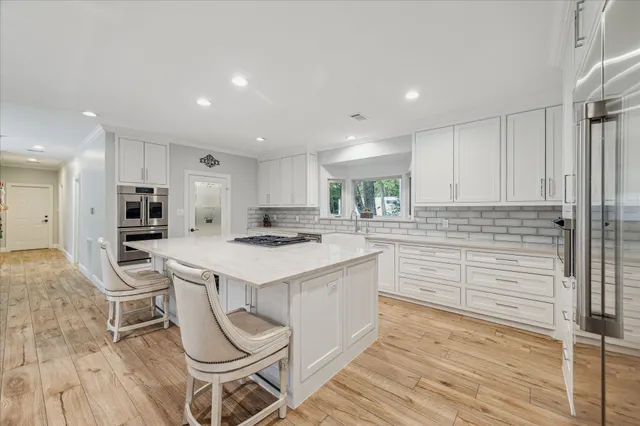 a large kitchen with kitchen island granite countertop a stove a sink a dining table and chairs