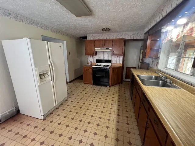 a kitchen with granite countertop a refrigerator stove and sink