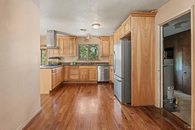 a kitchen with a sink wooden floor and stainless steel appliances