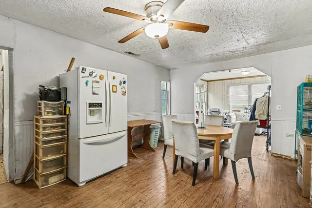 a kitchen with stainless steel appliances kitchen island granite countertop a table chairs and a refrigerator
