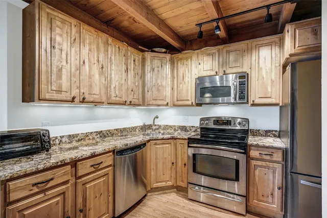 a kitchen with stainless steel appliances granite countertop a stove a sink and a microwave