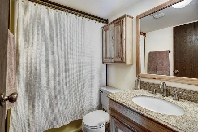 a bathroom with a granite countertop sink toilet and mirror