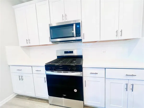 a kitchen with stainless steel appliances granite countertop white cabinets stove and a microwave