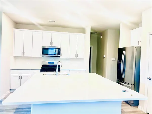 a kitchen with stainless steel appliances a refrigerator sink and white cabinets