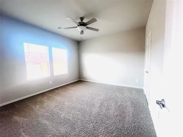 an empty room with windows and fan