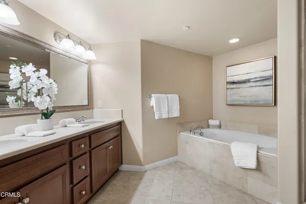 a bathroom with a double vanity sink mirror and bathtub