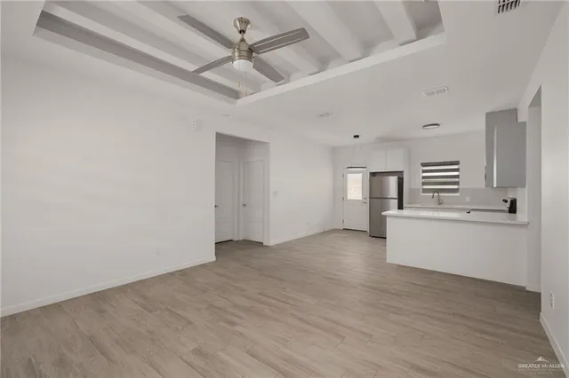 an empty room with wooden floor and a ceiling fan