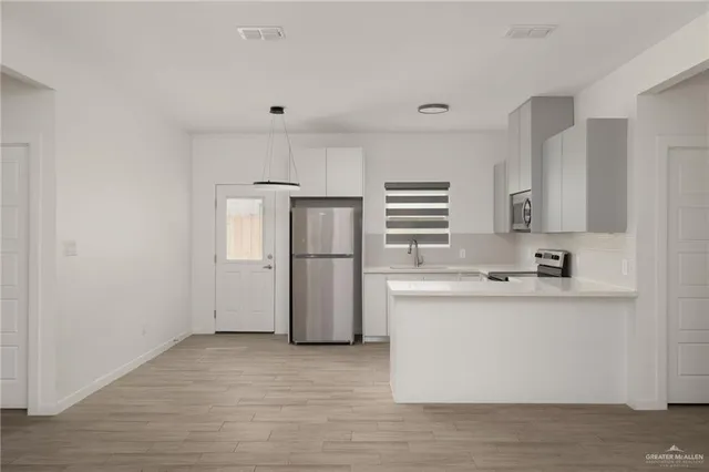 a kitchen with kitchen island a refrigerator sink and cabinets