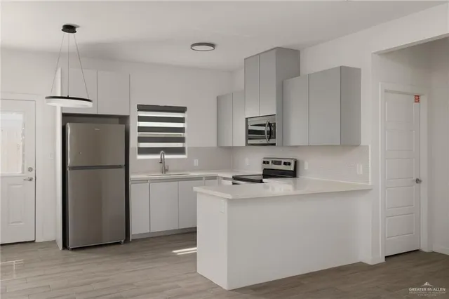 a kitchen with stainless steel appliances a refrigerator a sink and white cabinets