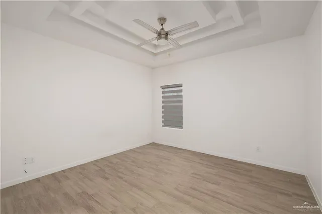 an empty room with a chandelier fan and windows