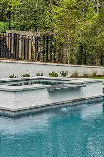 a white house with a large pool and lawn chairs next to a yard