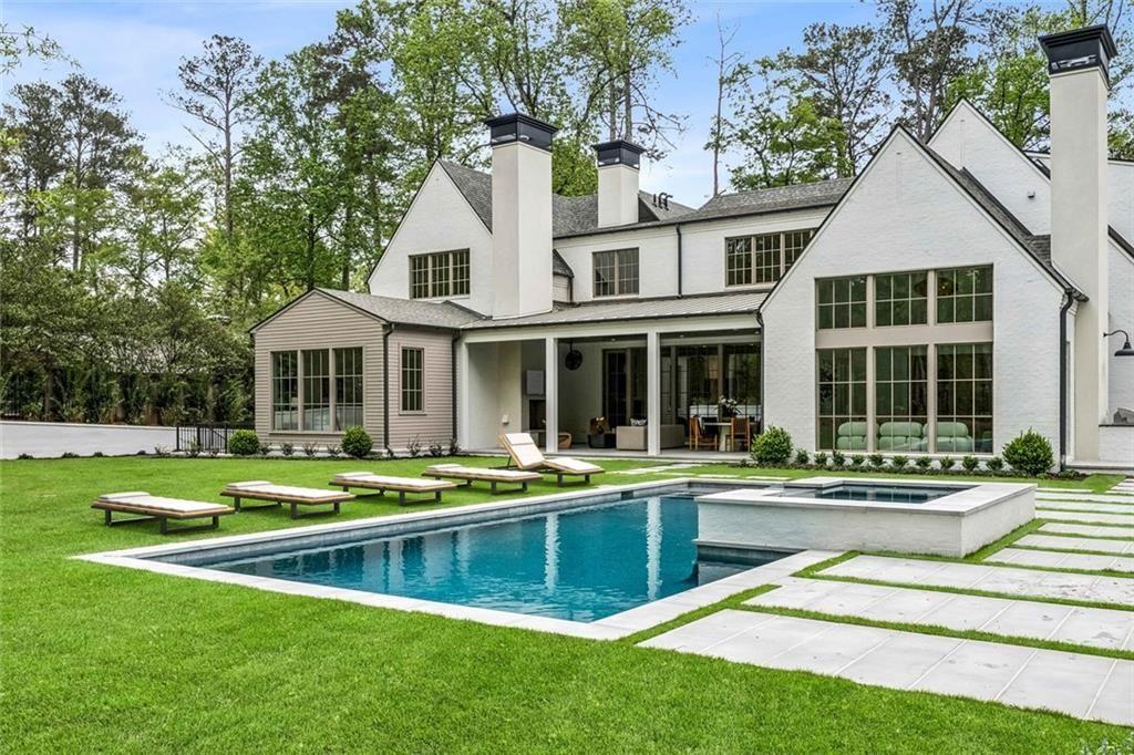 3167 Rilman Road Northwest Atlanta, GA 30327 - Photo 52 of 52 a white house with a large pool and lawn chairs next to a yard