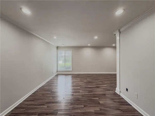 a view of an empty room with wooden floor and closet