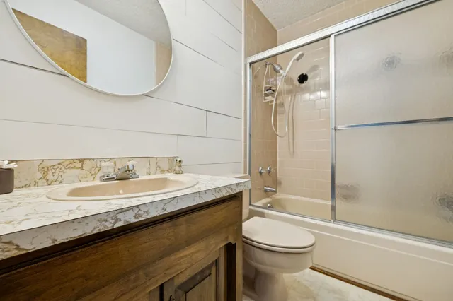 a bathroom with a granite countertop sink toilet a mirror and shower