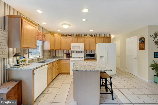 a large kitchen with stainless steel appliances kitchen island granite countertop a refrigerator and a stove top oven