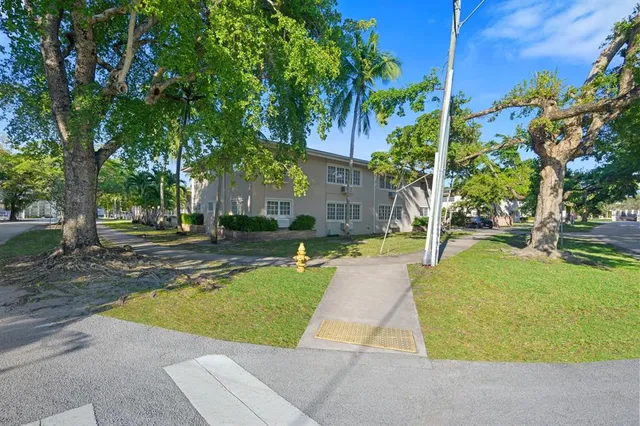 a car parked in front of yellow house with a large tree