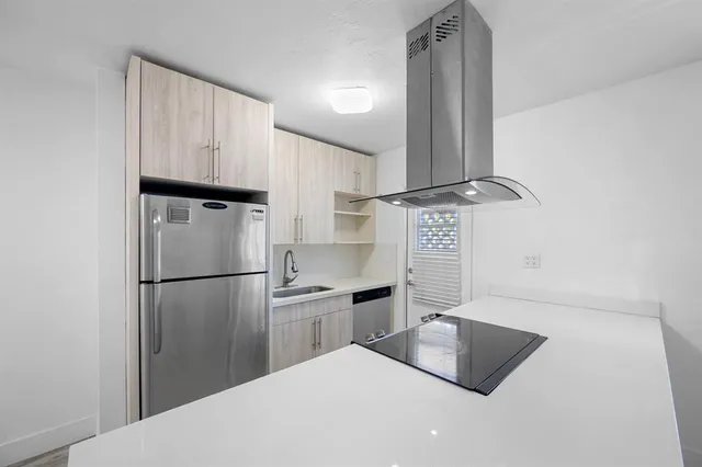 a kitchen with stainless steel appliances granite countertop a refrigerator a sink and white cabinets