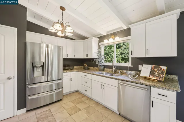 a kitchen with stainless steel appliances granite countertop a refrigerator and white cabinets