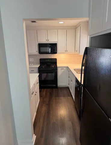 a kitchen with granite countertop a refrigerator stove and white cabinets