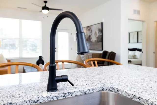 a kitchen with a sink a large window and a dining table with garden view