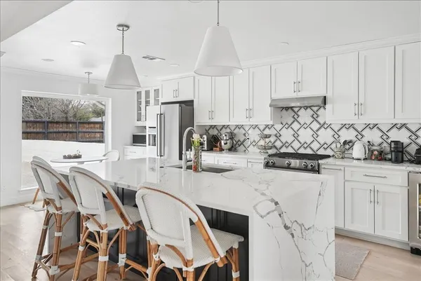 a kitchen with stainless steel appliances kitchen island granite countertop a table chairs sink and cabinets