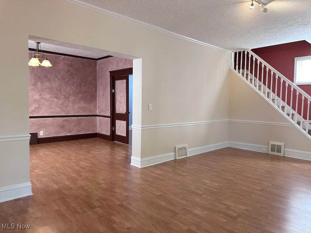 6846 Ottawa Road Cleveland, OH 44105 - Photo 7 of 50 Spare room with visible vents, a textured ceiling, stairs, and wood finished floors