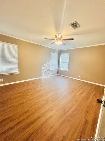a view of an empty room with wooden floor and a window