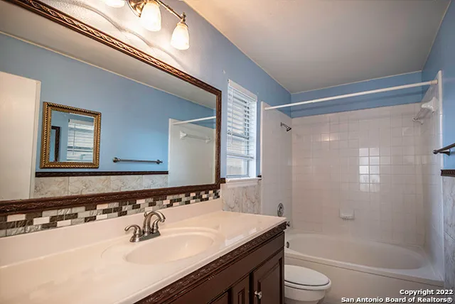 a bathroom with a sink a toilet a mirror and shower