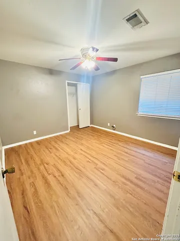 a view of an empty room with window and wooden floor