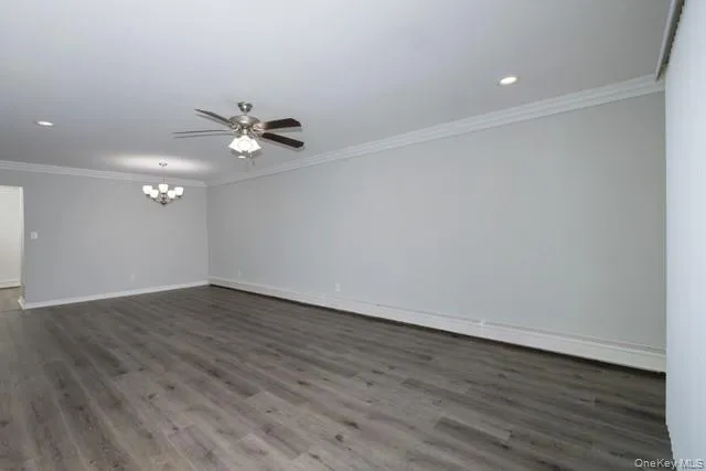 a view of an empty room with wooden floor and a ceiling fan