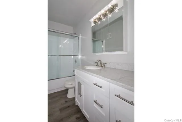 a bathroom with a granite countertop sink a toilet and a mirror