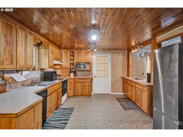 a kitchen with stainless steel appliances granite countertop a refrigerator a sink a stove and a refrigerator with wooden cabinets