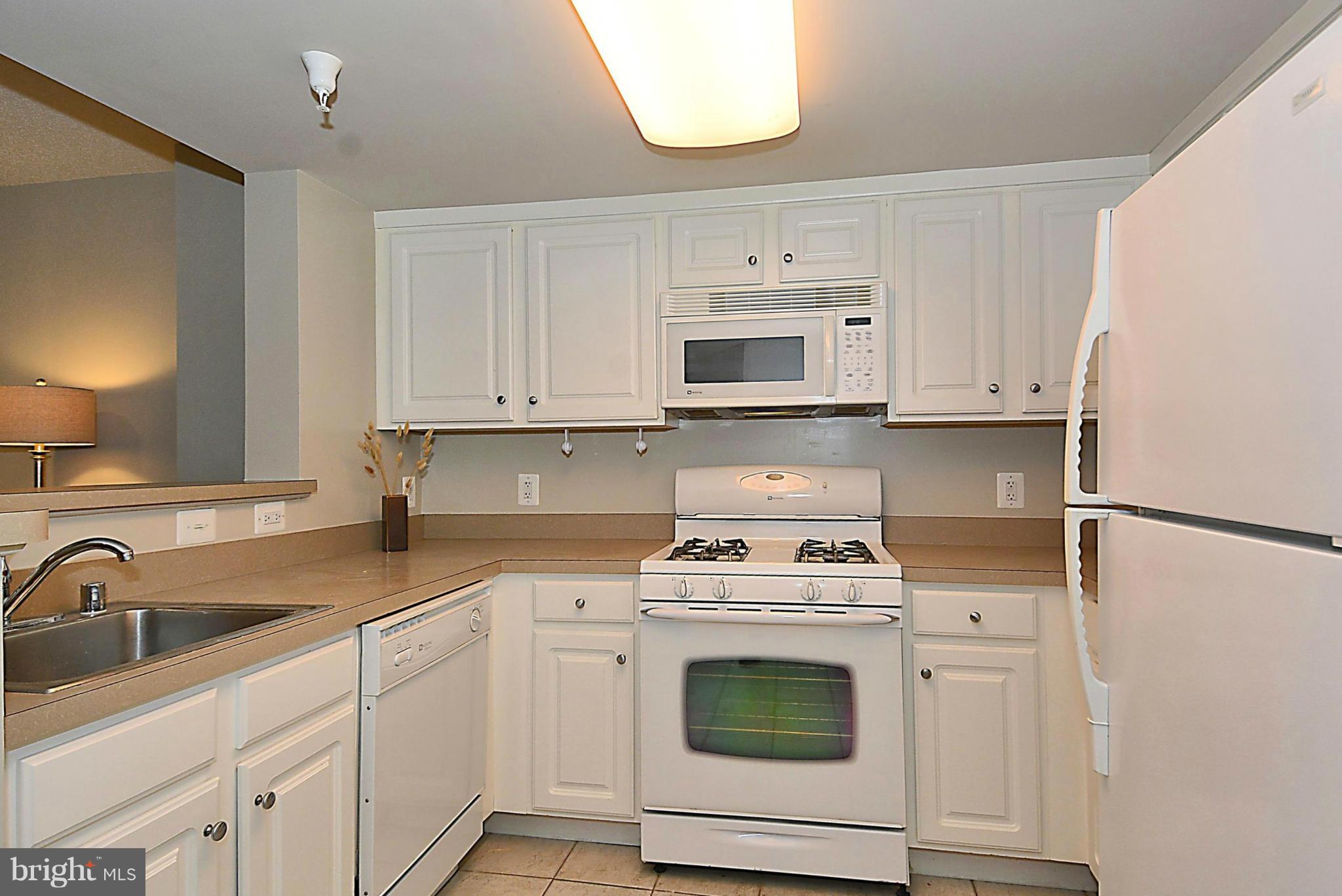 11710 Old Georgetown Road, Unit 419 North Bethesda, MD 20852 - Photo 7 of 30 a kitchen with white cabinets and white appliances