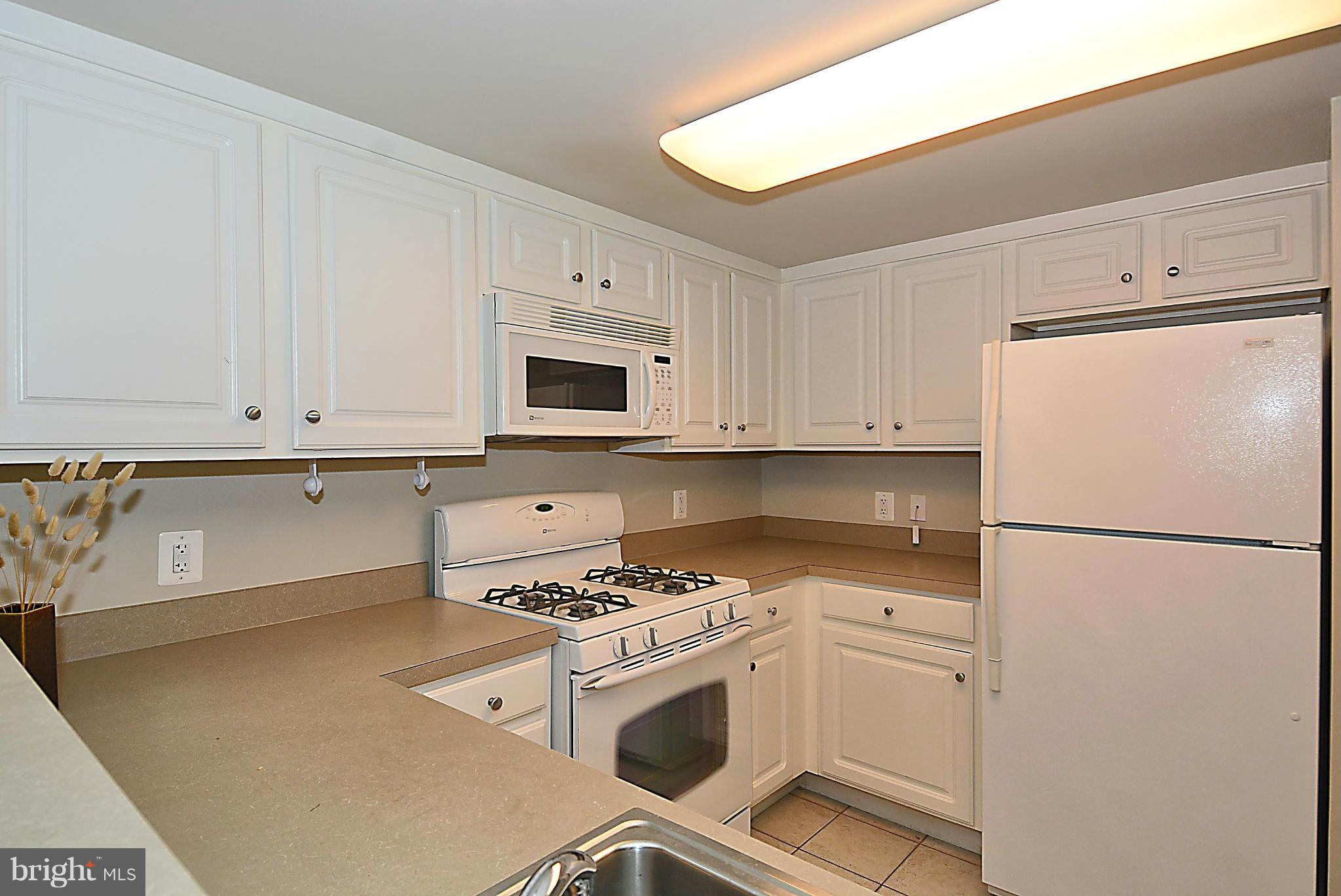 11710 Old Georgetown Road, Unit 419 North Bethesda, MD 20852 - Photo 8 of 30 a kitchen with white cabinets and white appliances