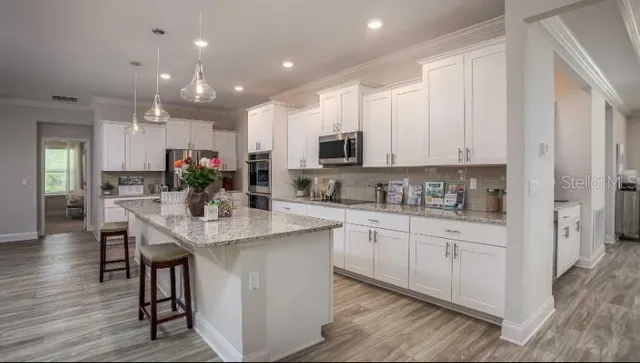 a kitchen with kitchen island granite countertop a sink cabinets and wooden floor